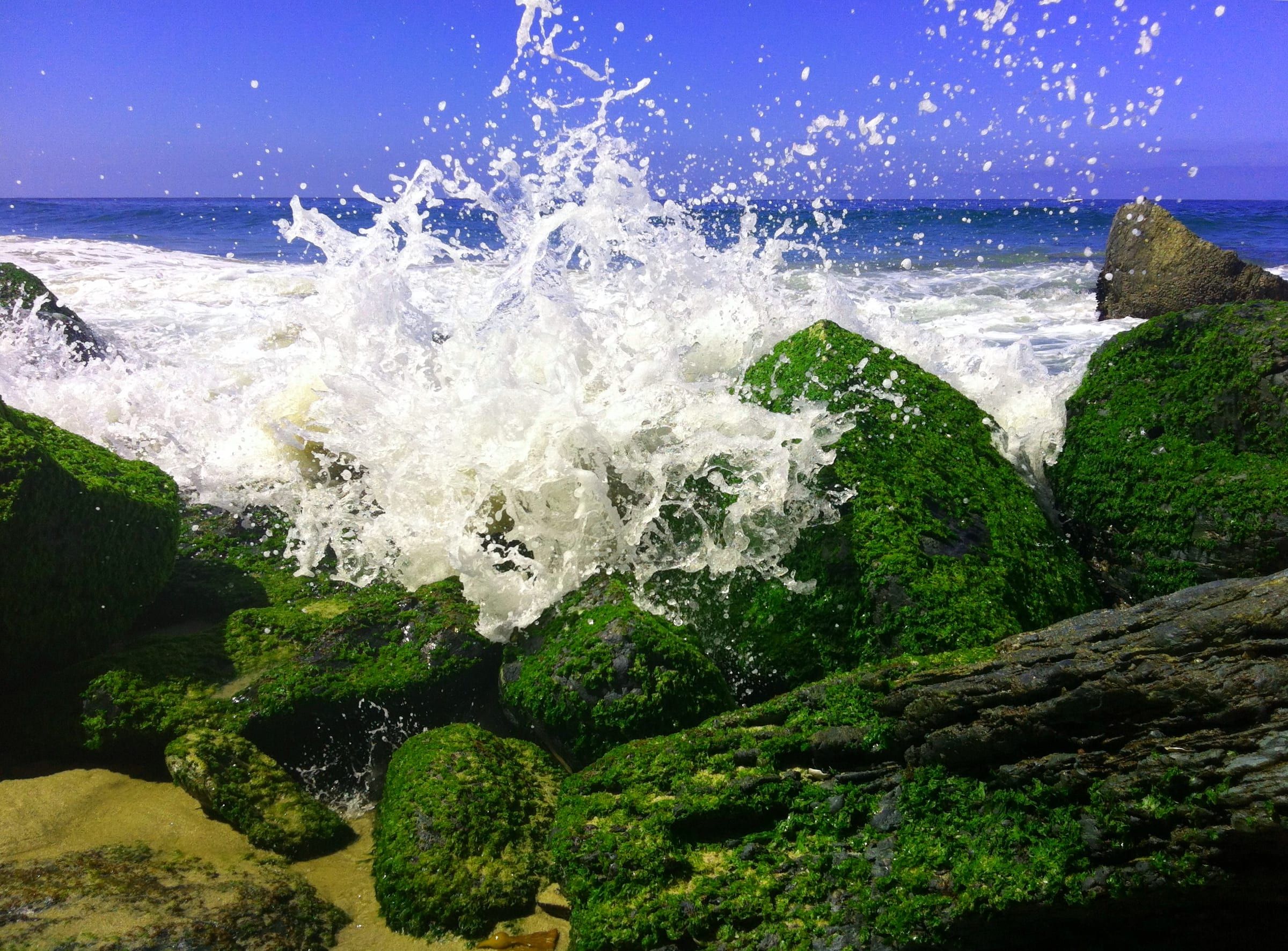 Waves splashing over moss-covered rocks at Thousand Steps Beach