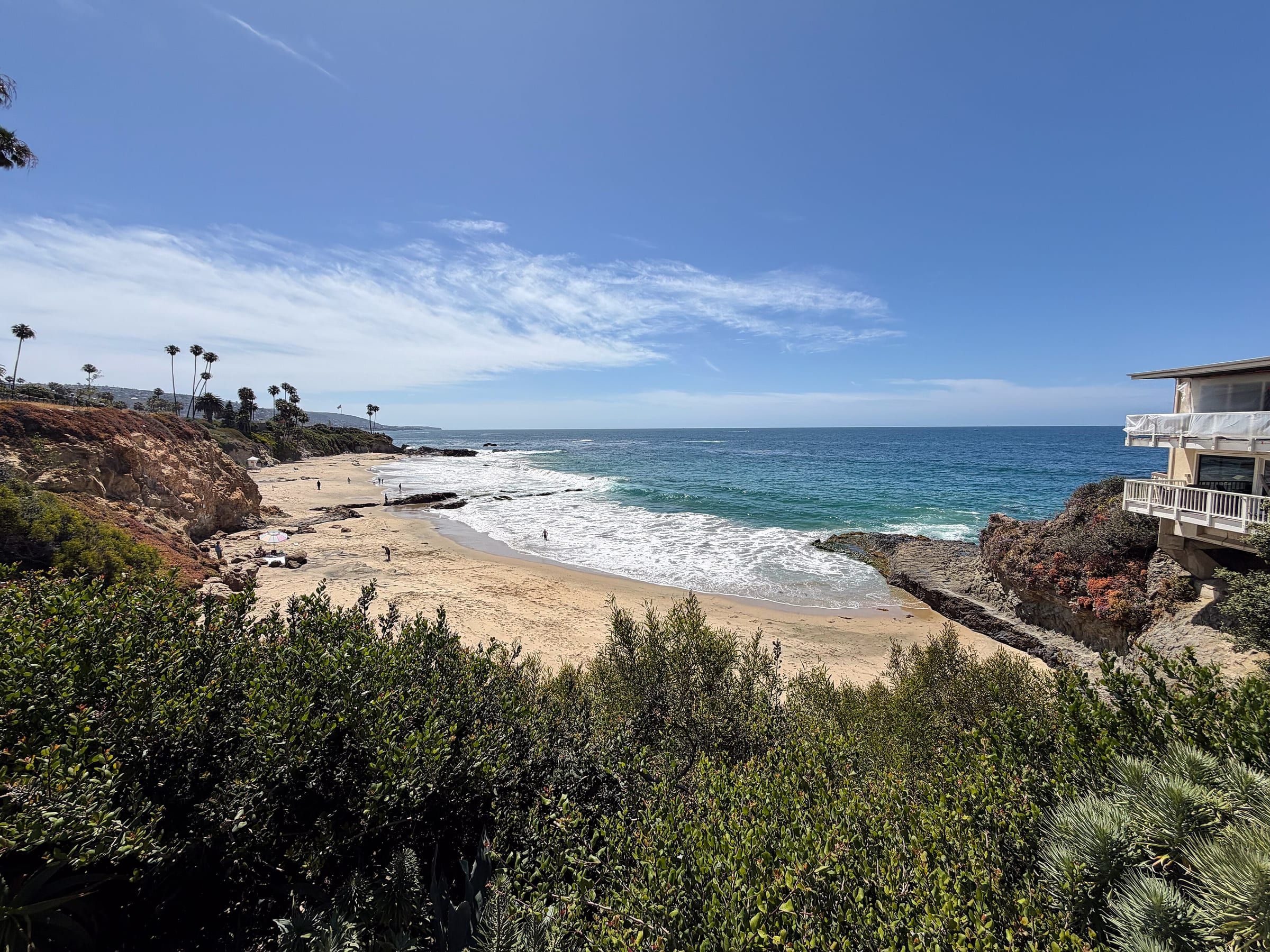 A sandy cove at Divers Cove in Laguna Beach with surf, rocky points and bluffs, photographed in April 2026