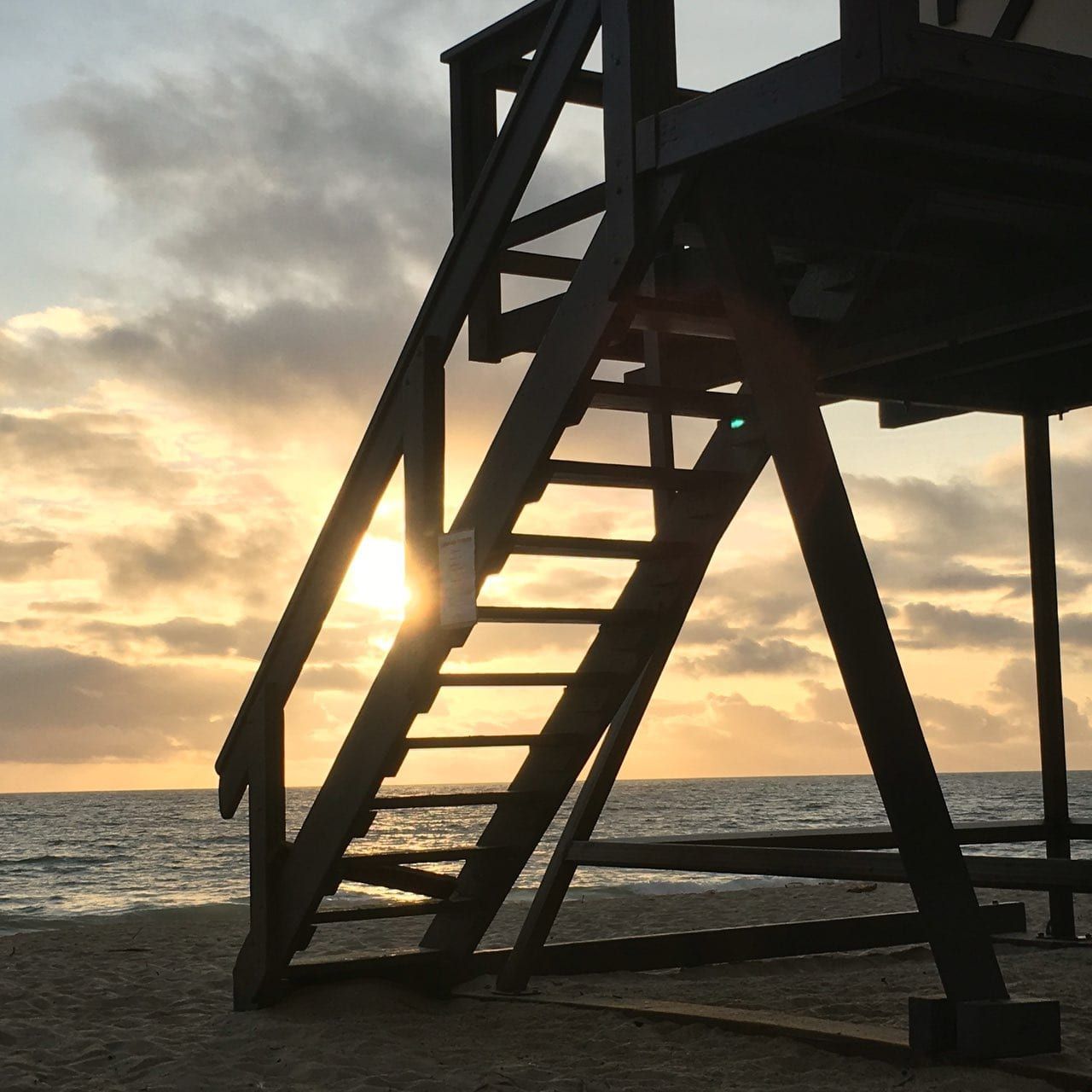 Sunset seen through the steps of a lifeguard tower at Aliso Creek Beach