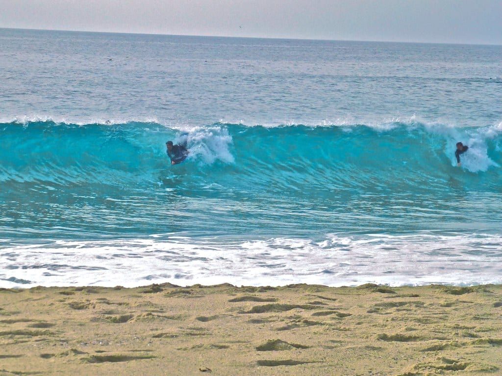 Two people boogie boarding a wave at Thousand Steps Beach